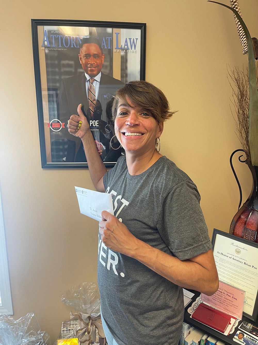 A woman is holding a check in front of a picture of a man in a suit and tie