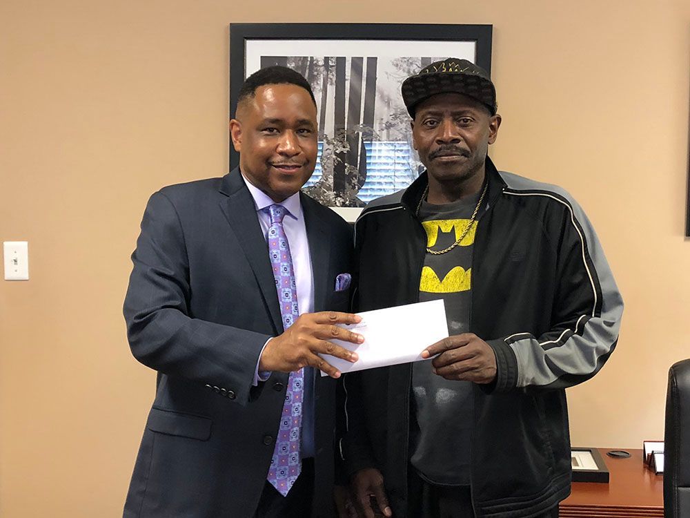 A man in a suit and tie is giving a check to another man