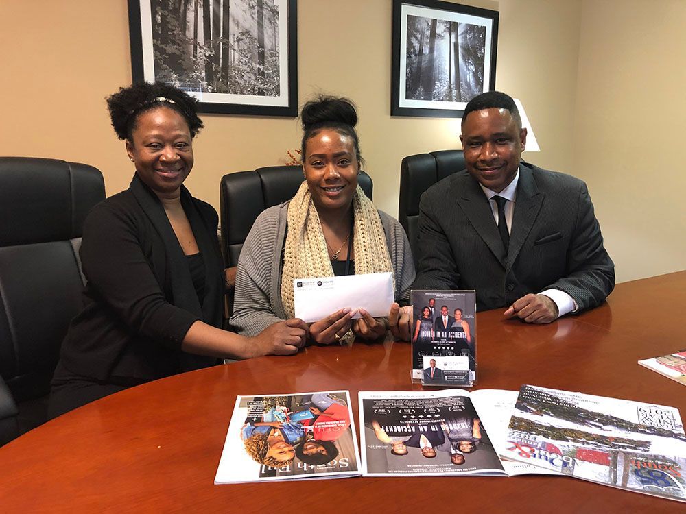 A man and two women are sitting at a table with magazines on it