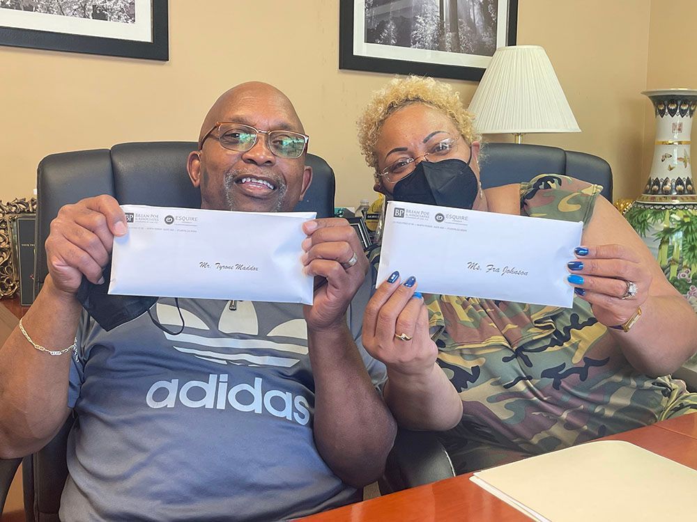 A man and a woman are sitting at a table holding envelopes