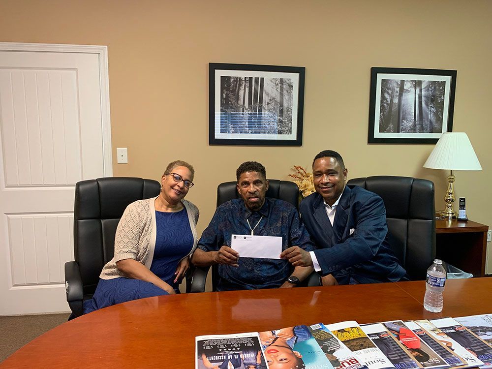Two men and a woman are sitting at a table holding a check