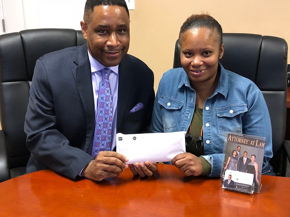 Brian D. Poe, Esq. and his client sitting at a table holding an envelope