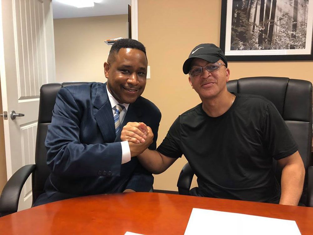 Brian D. Poe, Esq. and his client are shaking hands while sitting at a table