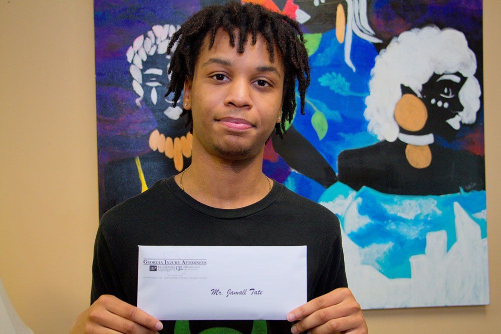 A young man is holding an envelope in front of a painting