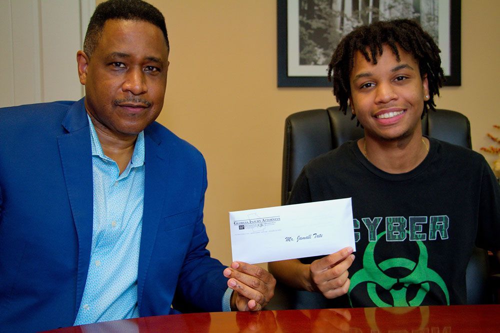 Brian D. Poe, Esq. and his client are sitting at a table holding a check