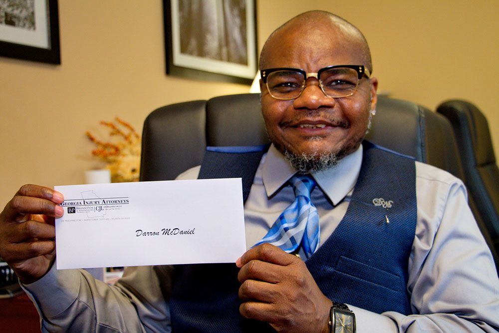 A man in a suit and tie is holding a check in his hand
