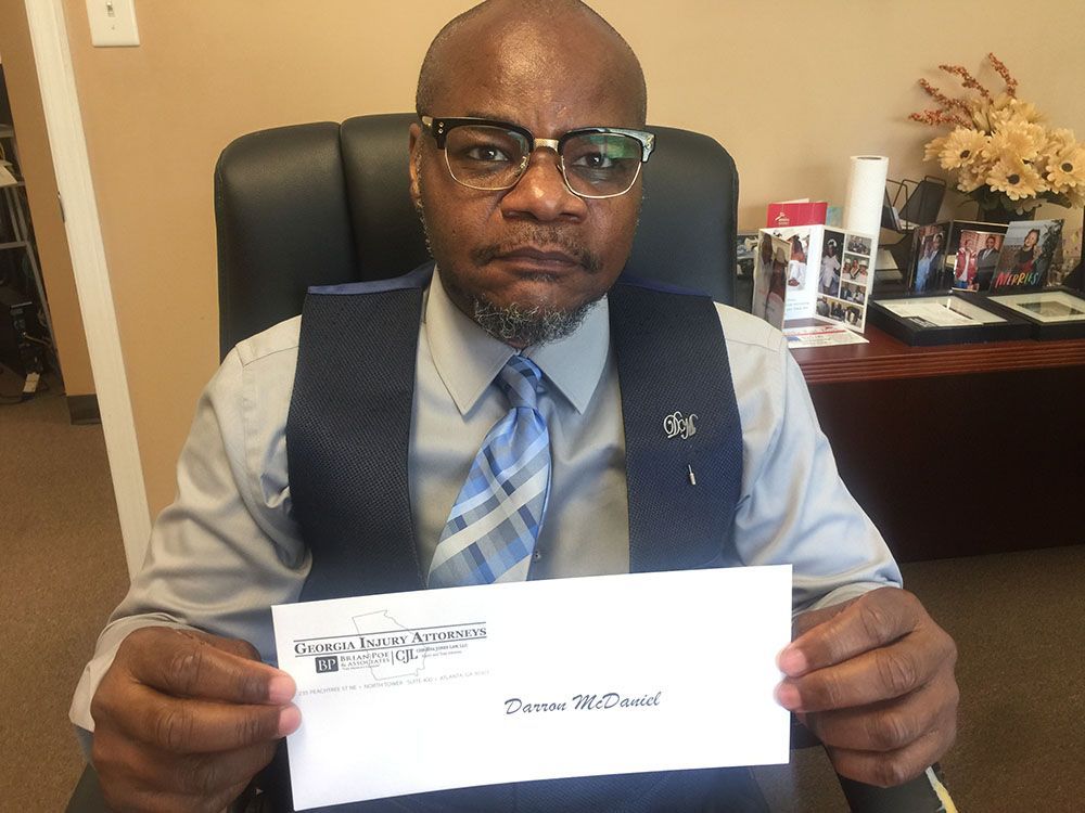 A man wearing eyeglasses is holding an envelope