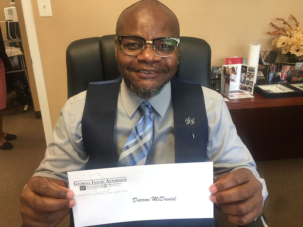 A man wearing glasses and a tie is holding an envelope
