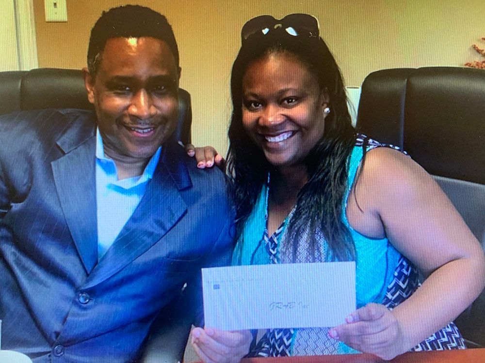 Brian D. Poe, Esq. and a happy client holding a check