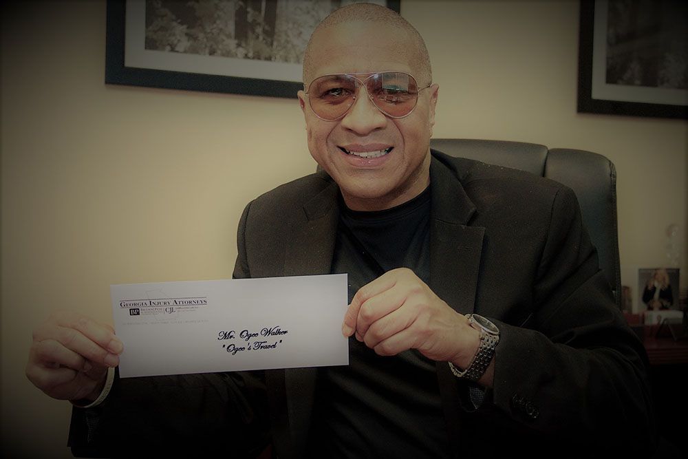 A man in a suit and glasses is holding an envelope