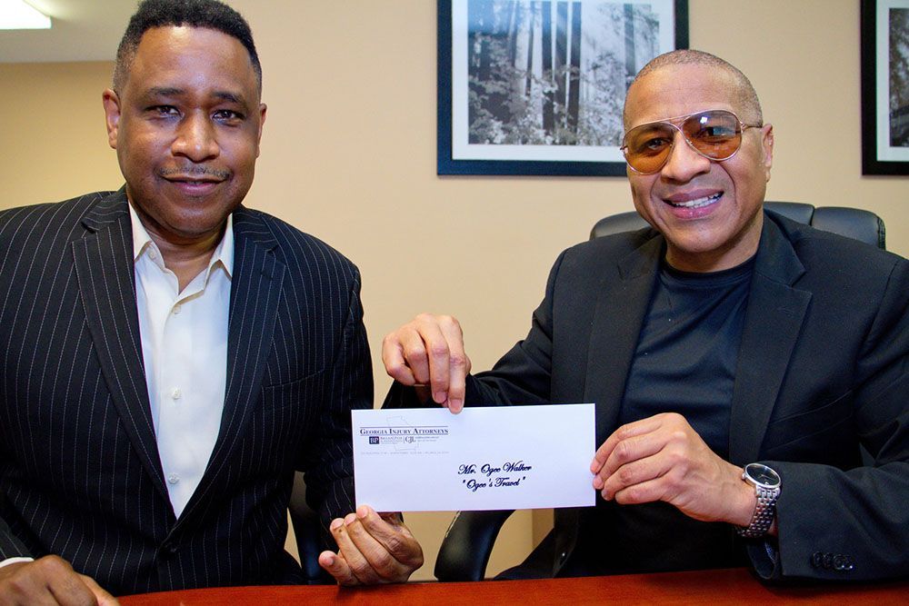 Two men are sitting at a table holding an envelope