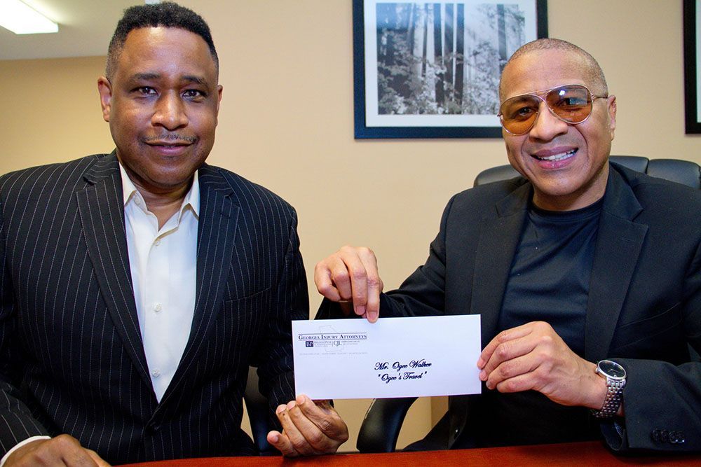 Brian D. Poe, Esq. holding a check with a happy client
