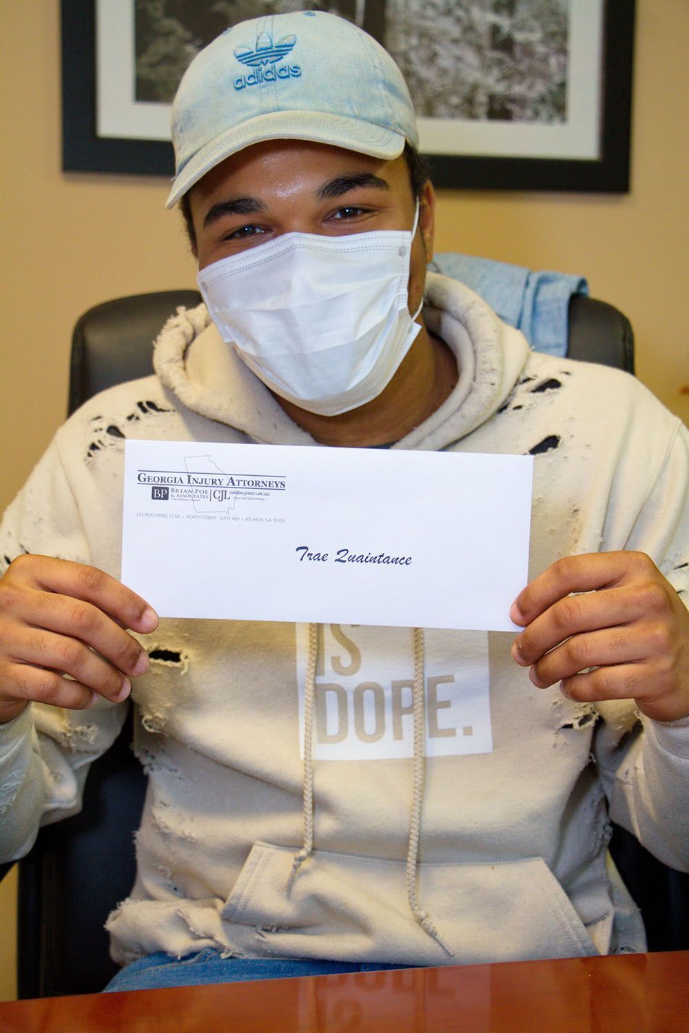 A man wearing a face mask is holding an envelope