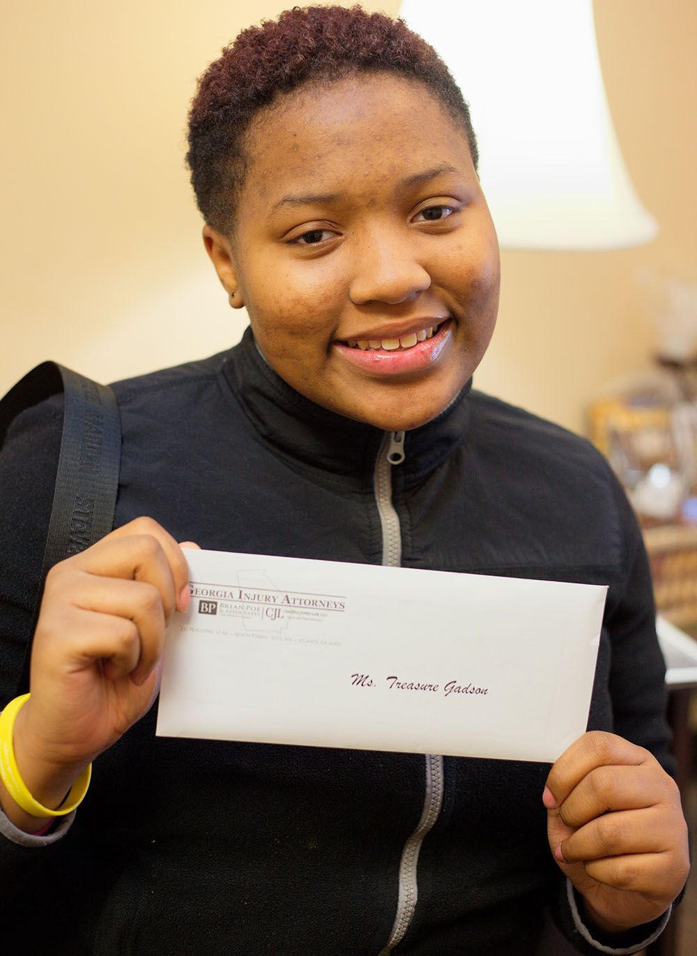 A woman in a black jacket is holding a check