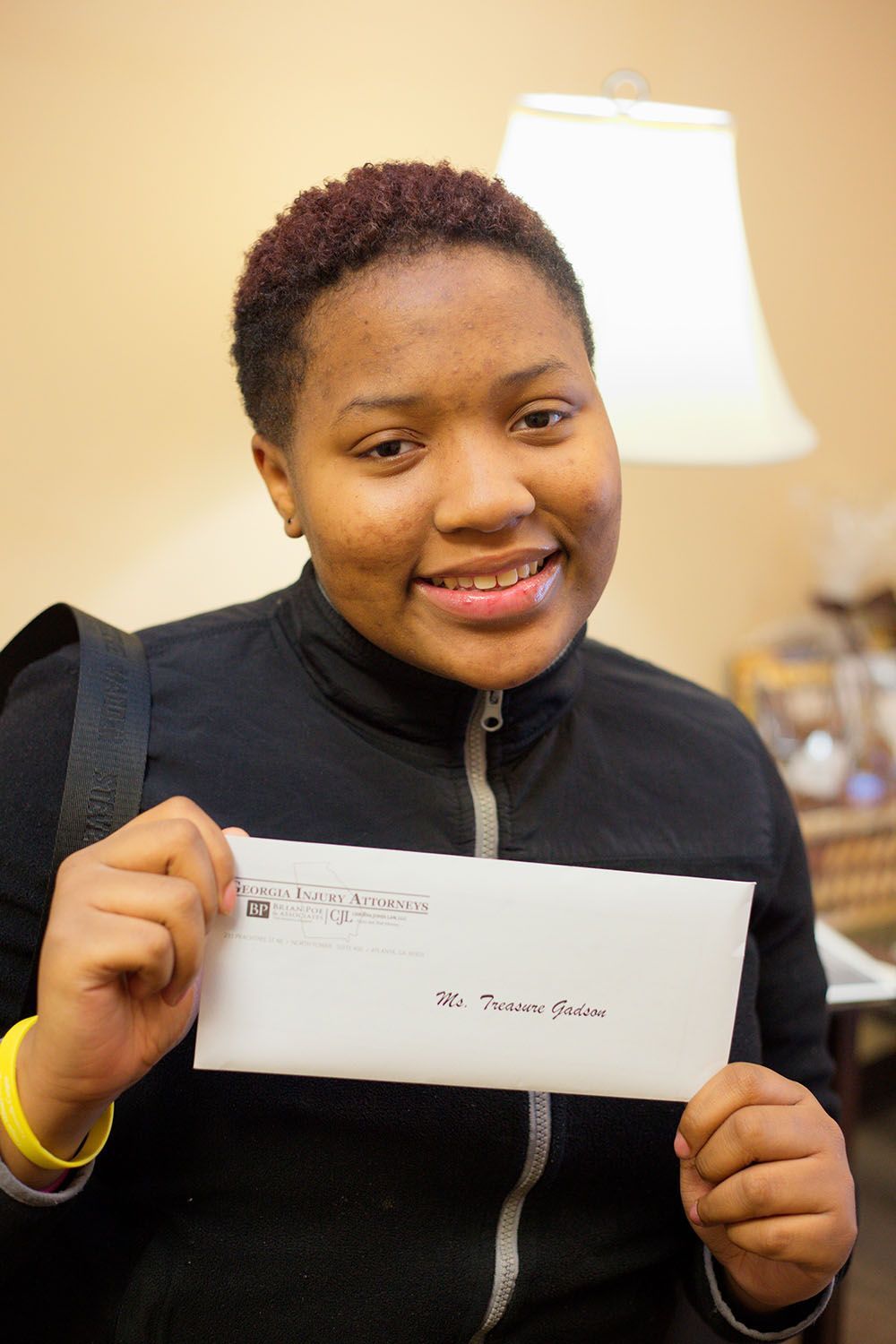 A happy woman in a black jacket holding an envelope