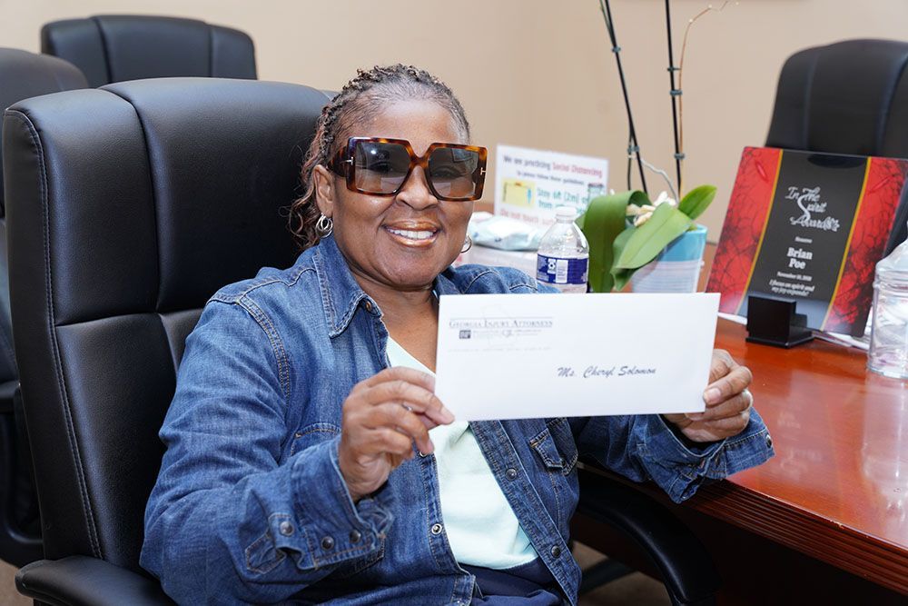 A woman wearing sunglasses is sitting in a chair holding a check