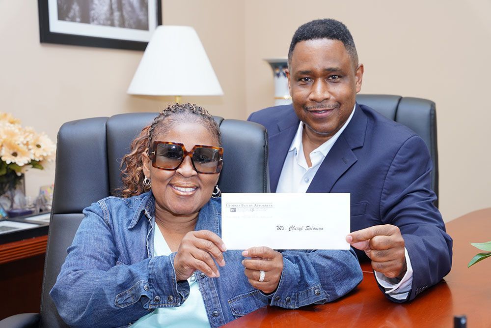 Brian D. Poe, Esq. and a happy client are sitting at a desk holding a check