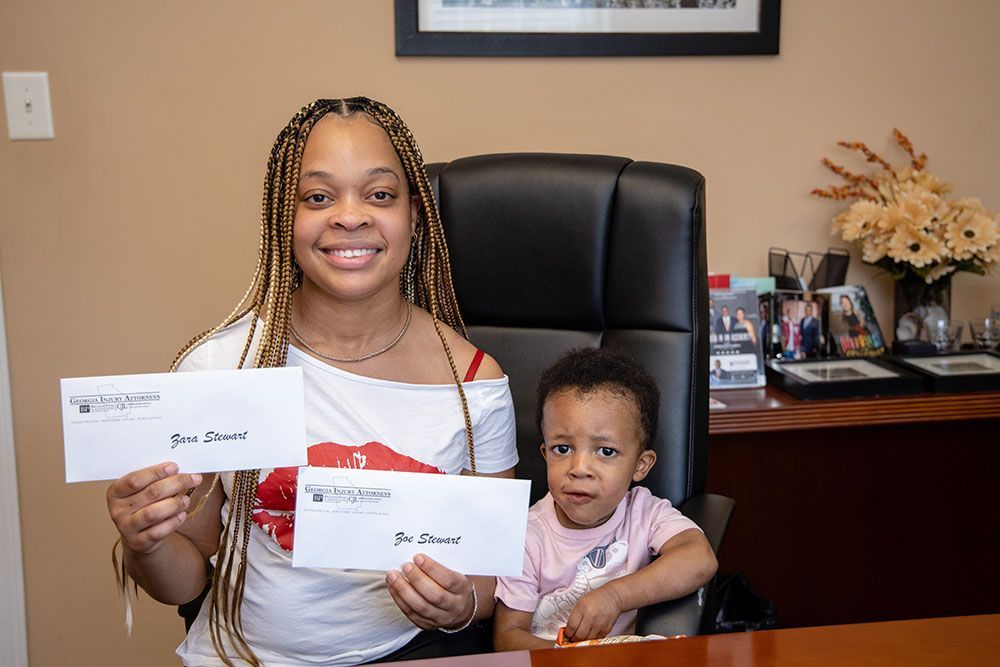 A woman and a child are sitting at a desk holding envelopes