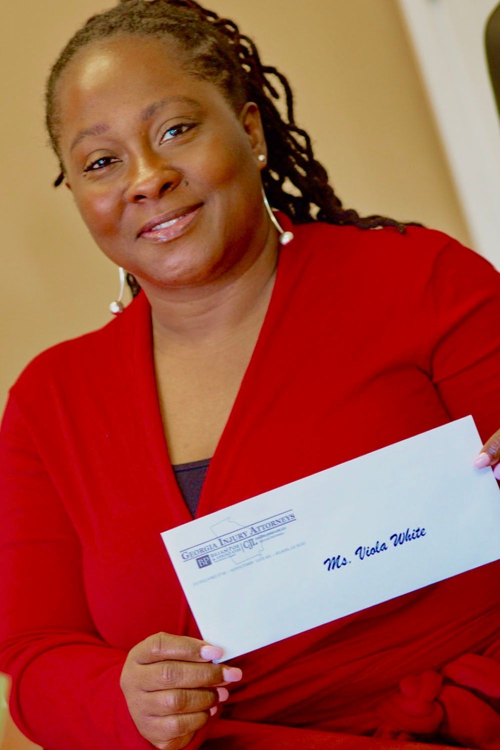 A woman in red is holding a check