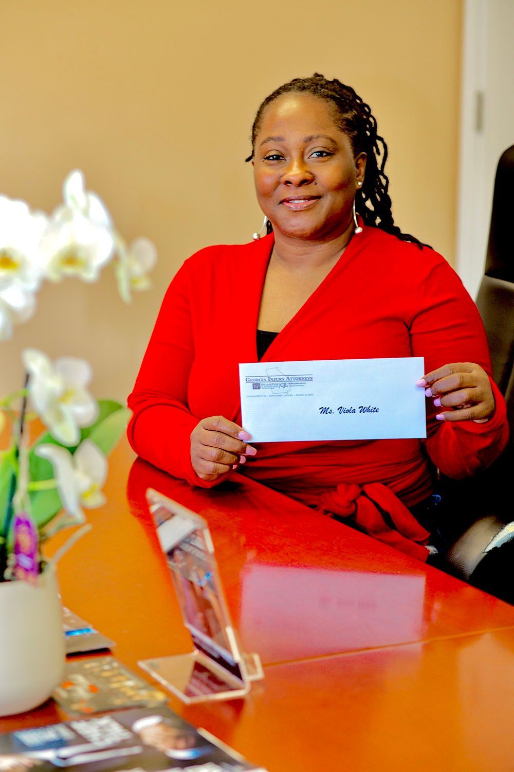 A happy woman in a red dress is sitting at a table holding a check