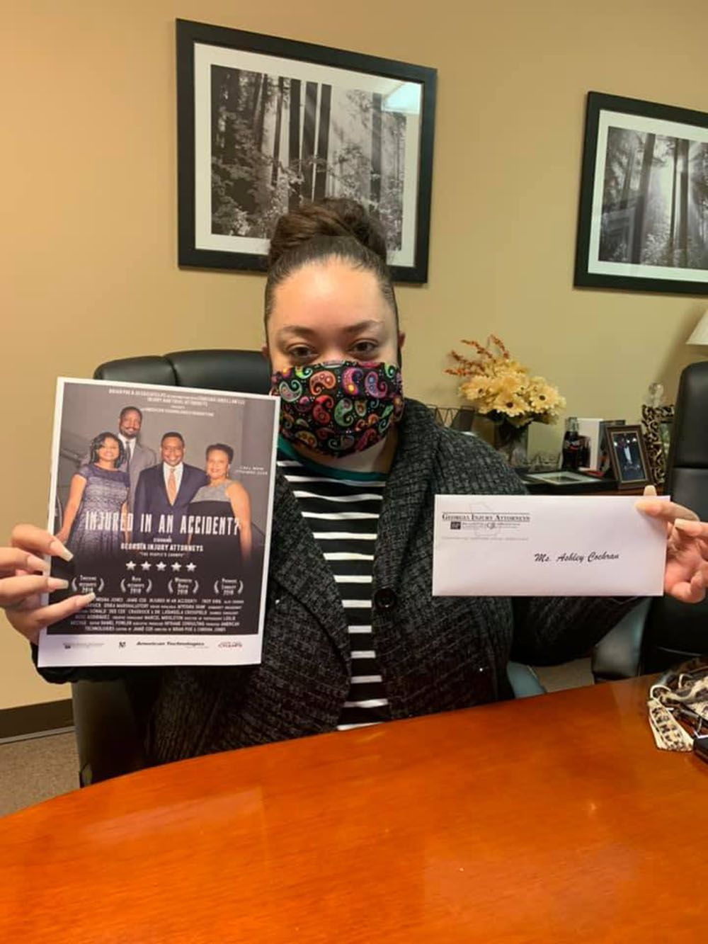 A woman wearing a mask is holding a flyer and an envelope