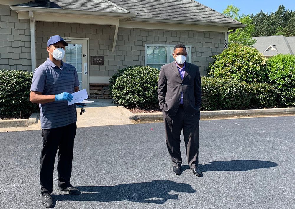 Brian D. Poe, Esq. and a happy client are standing in front of a building