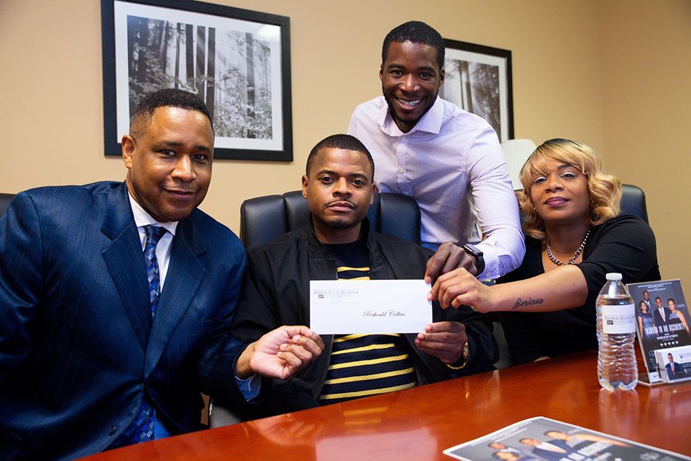 A group of happy people are sitting around a table holding a check