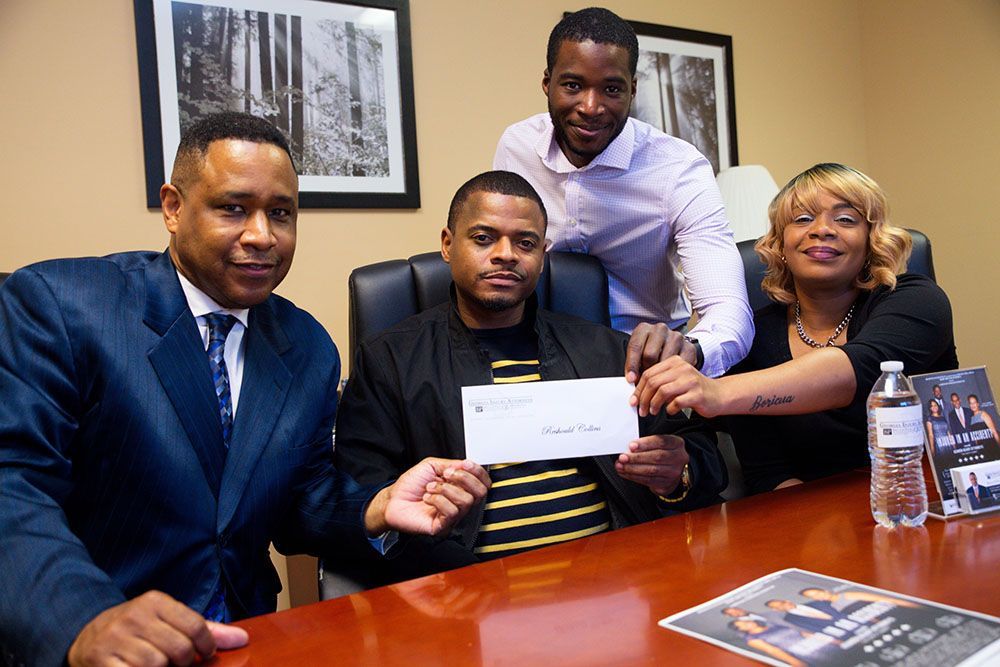 Georgia Injury Attorneys and a very happy client holding a check