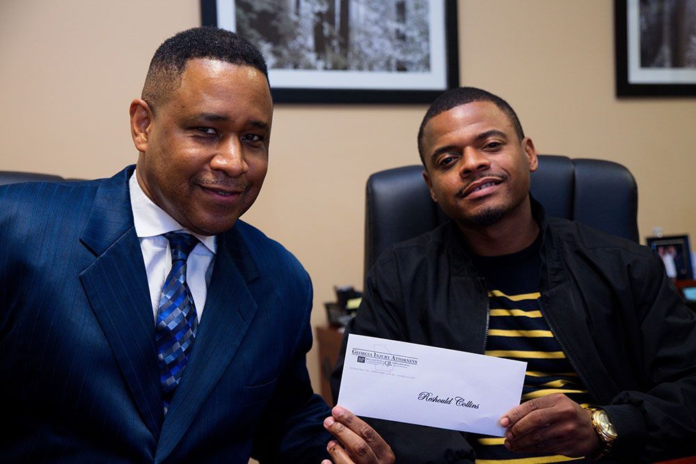 Brian D. Poe, Esq. handing a check to a happy client wearing black shirt