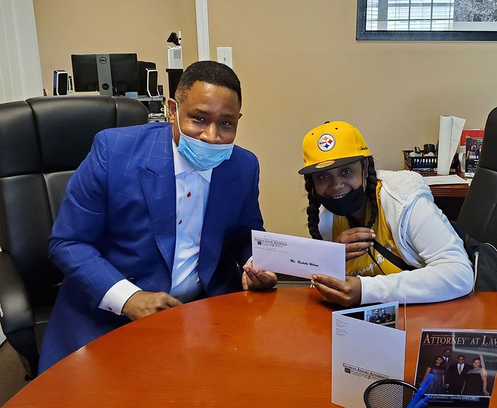 Brian D. Poe, Esq. and a woman wearing masks are sitting at a table