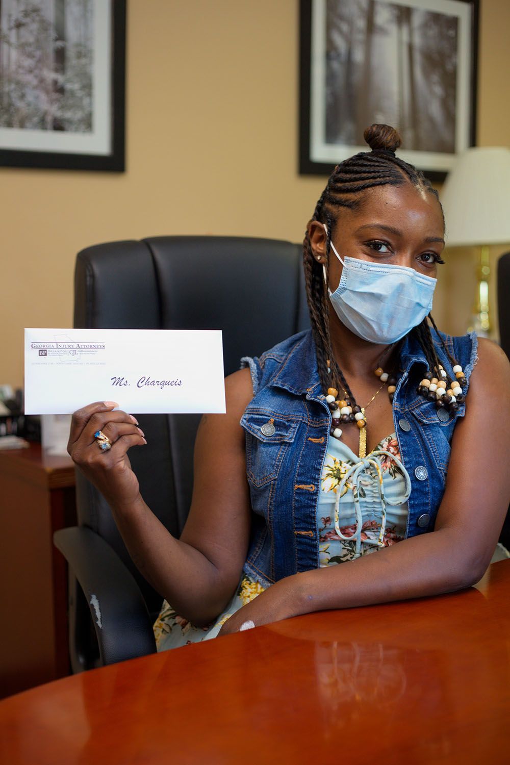 A client wearing a mask is sitting at a desk holding a check