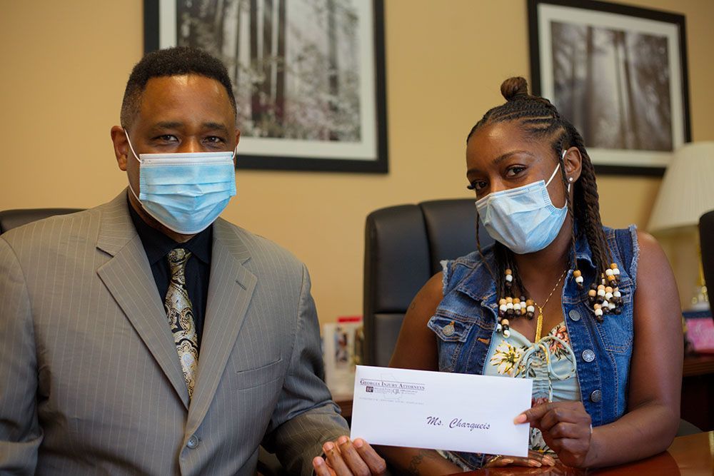 Brian D. Poe, Esq. is handing a check to a happy female client