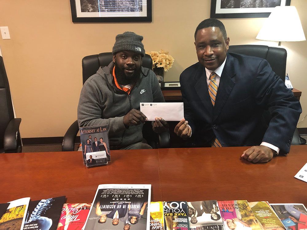 Brian D. Poe, Esq. handing a check to a very happy male client