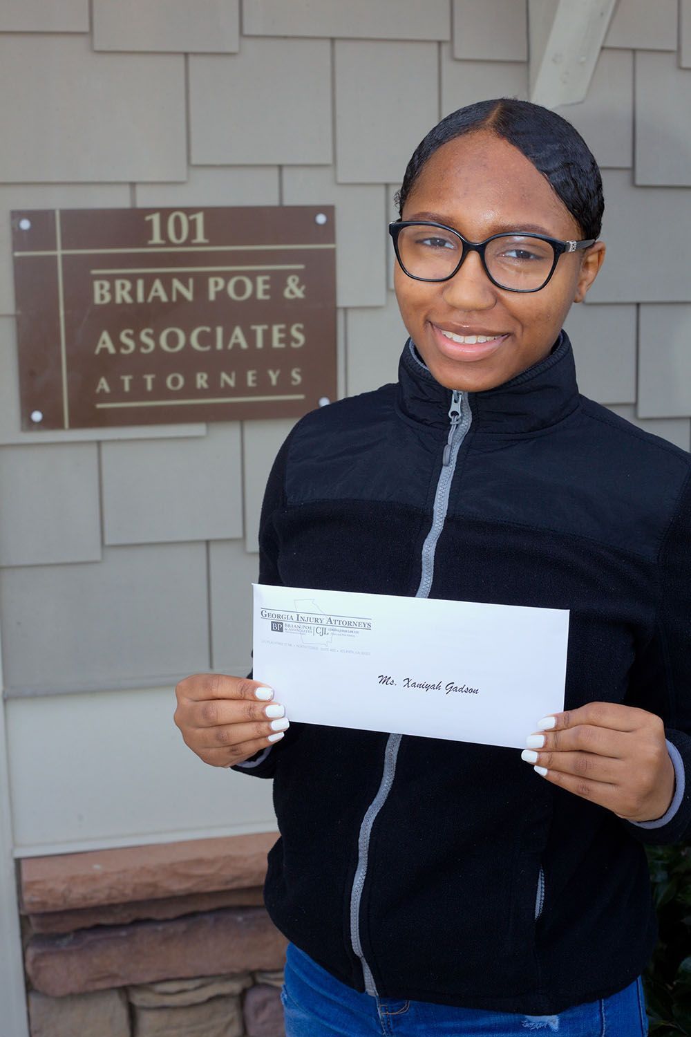 A woman wearing black jacket is holding a check