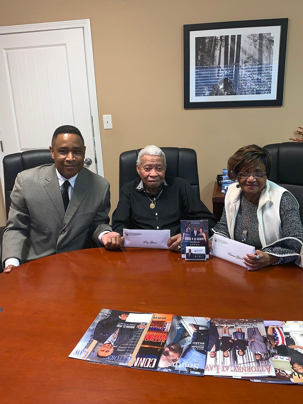 Happy clients are sitting at a table holding envelopes