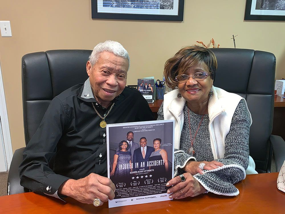 Happy clients are sitting at a table holding a flyer