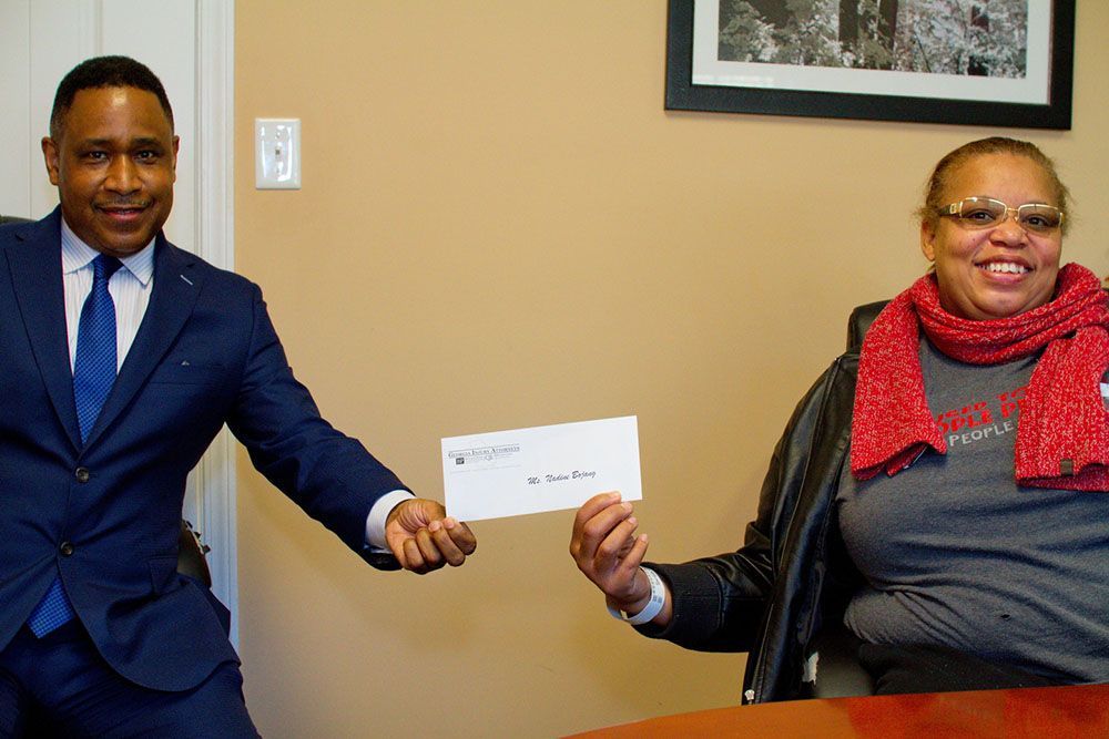 Brian D. Poe, Esq. giving a woman a check