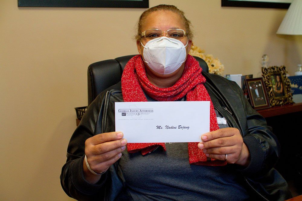 A woman wearing a mask is holding an envelope