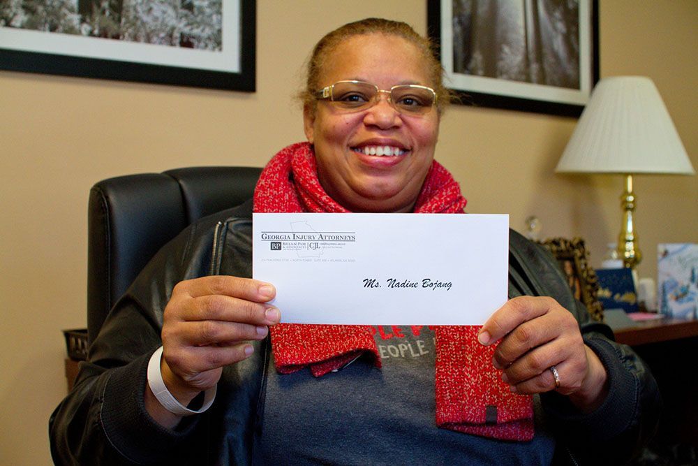 A woman is sitting in a chair holding an envelope
