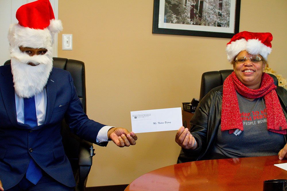 Brian D. Poe, Esq. dressed as Santa Claus is giving a woman a check