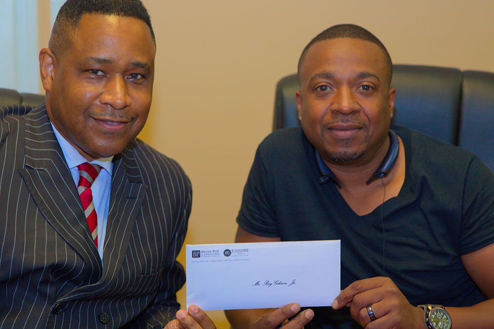 Brian D. Poe, Esq. is handing an envelope to a client