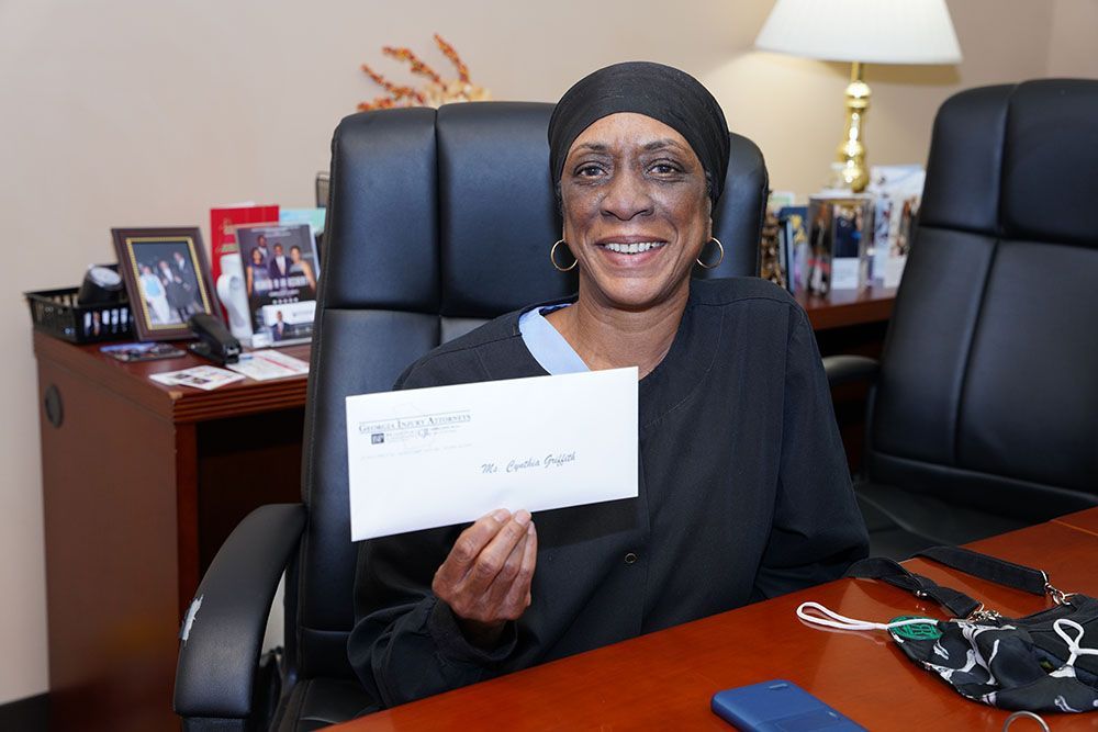 A smiling woman is sitting at a desk holding an envelope