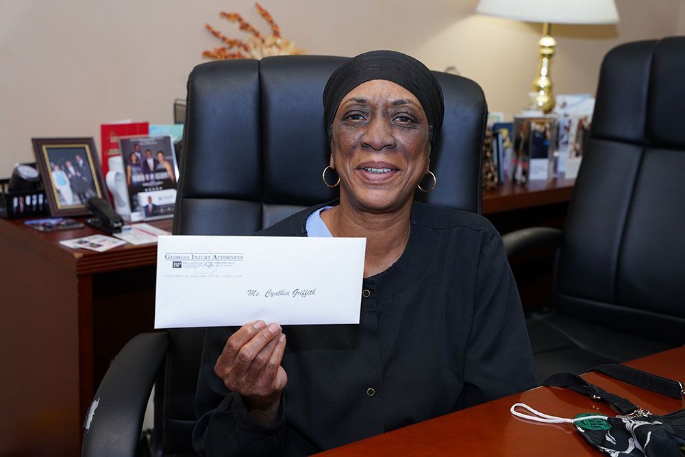 A woman is sitting in a chair holding a check in her hand