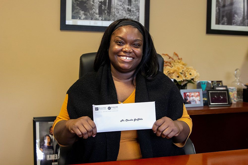A happy female client is sitting at a desk holding a check