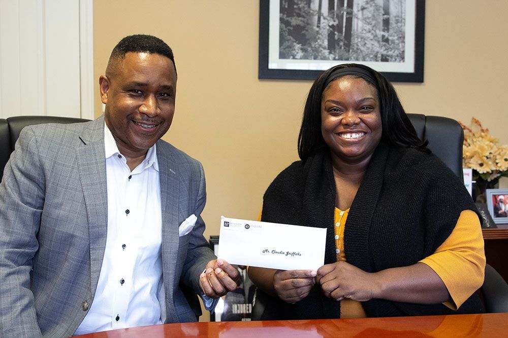 Brian D. Poe, Esq. handing a check to a smiling client