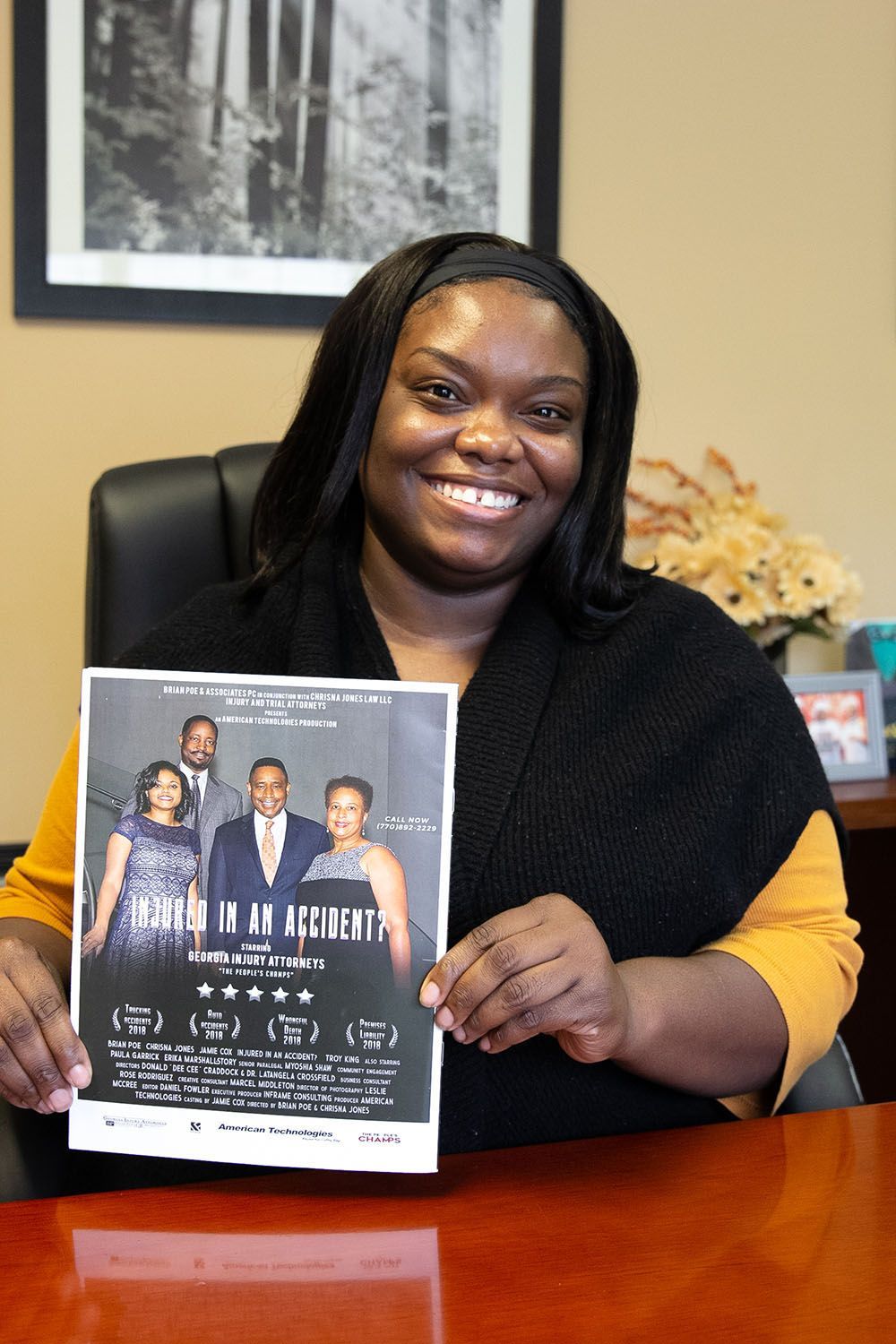 A woman is sitting at a desk holding a flyer