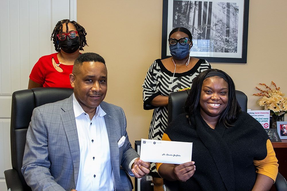 A man and a woman are sitting in a chair holding a check