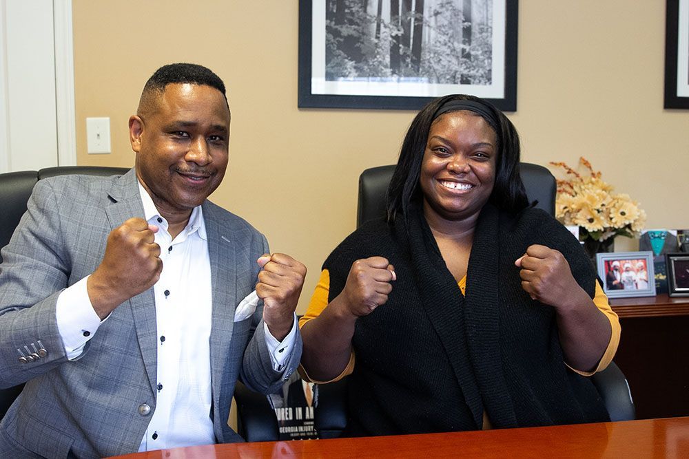 A man and a woman are sitting at a table with their fists in the air