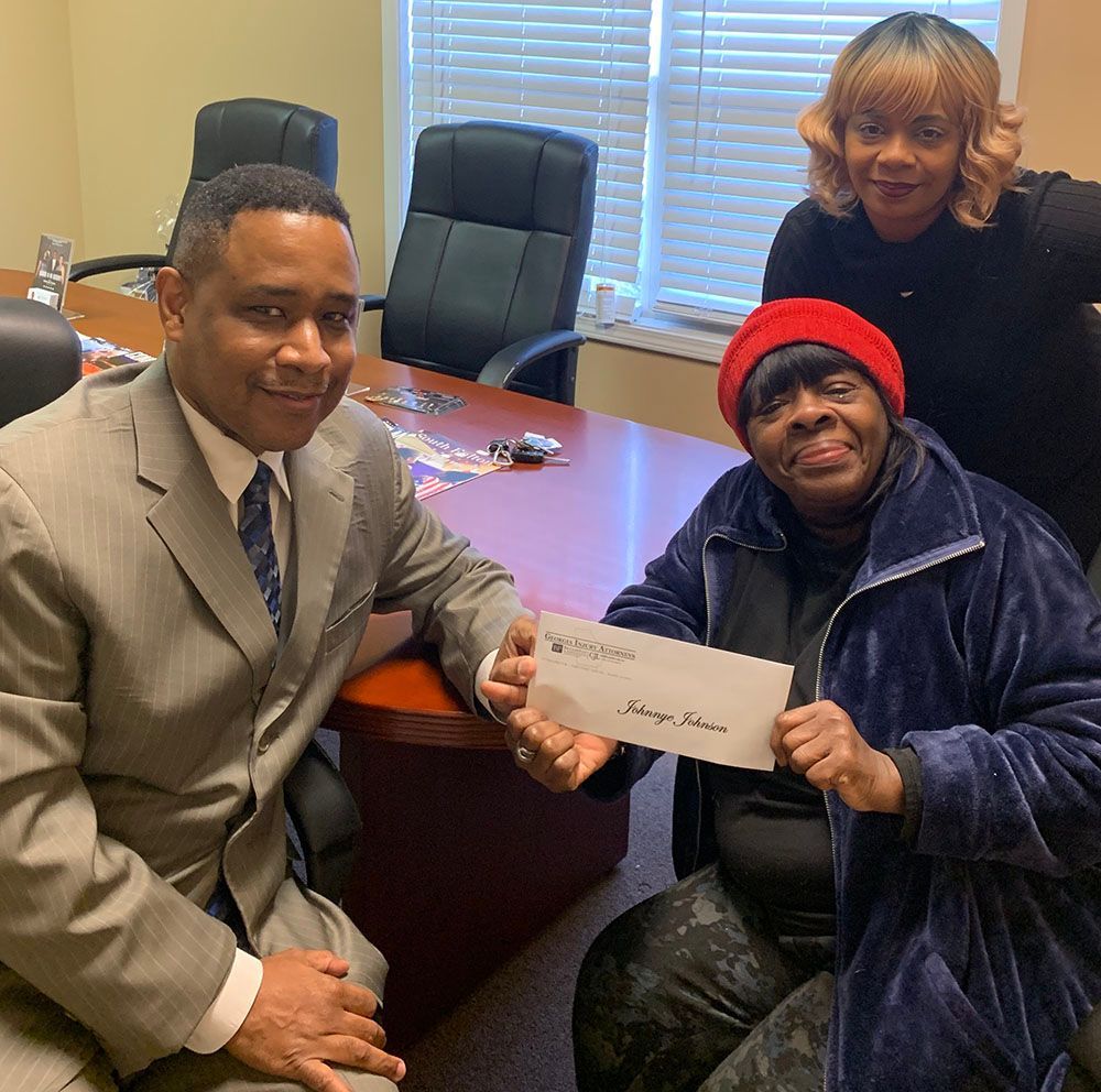 Brian D. Poe, Esq. handing a check to a client in a red hat