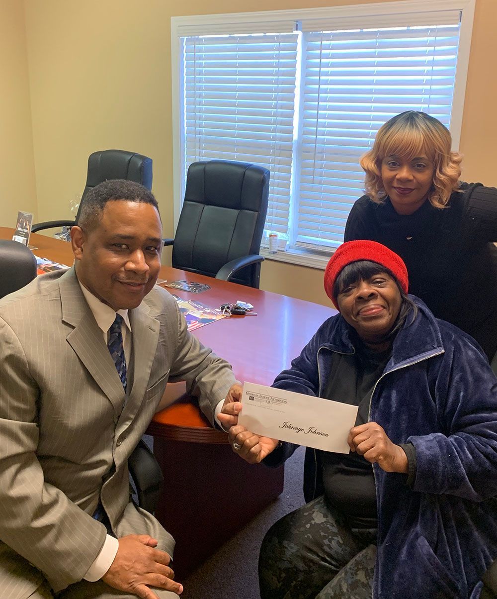 Brian D. Poe, Esq. handing a check to a woman in a red hat